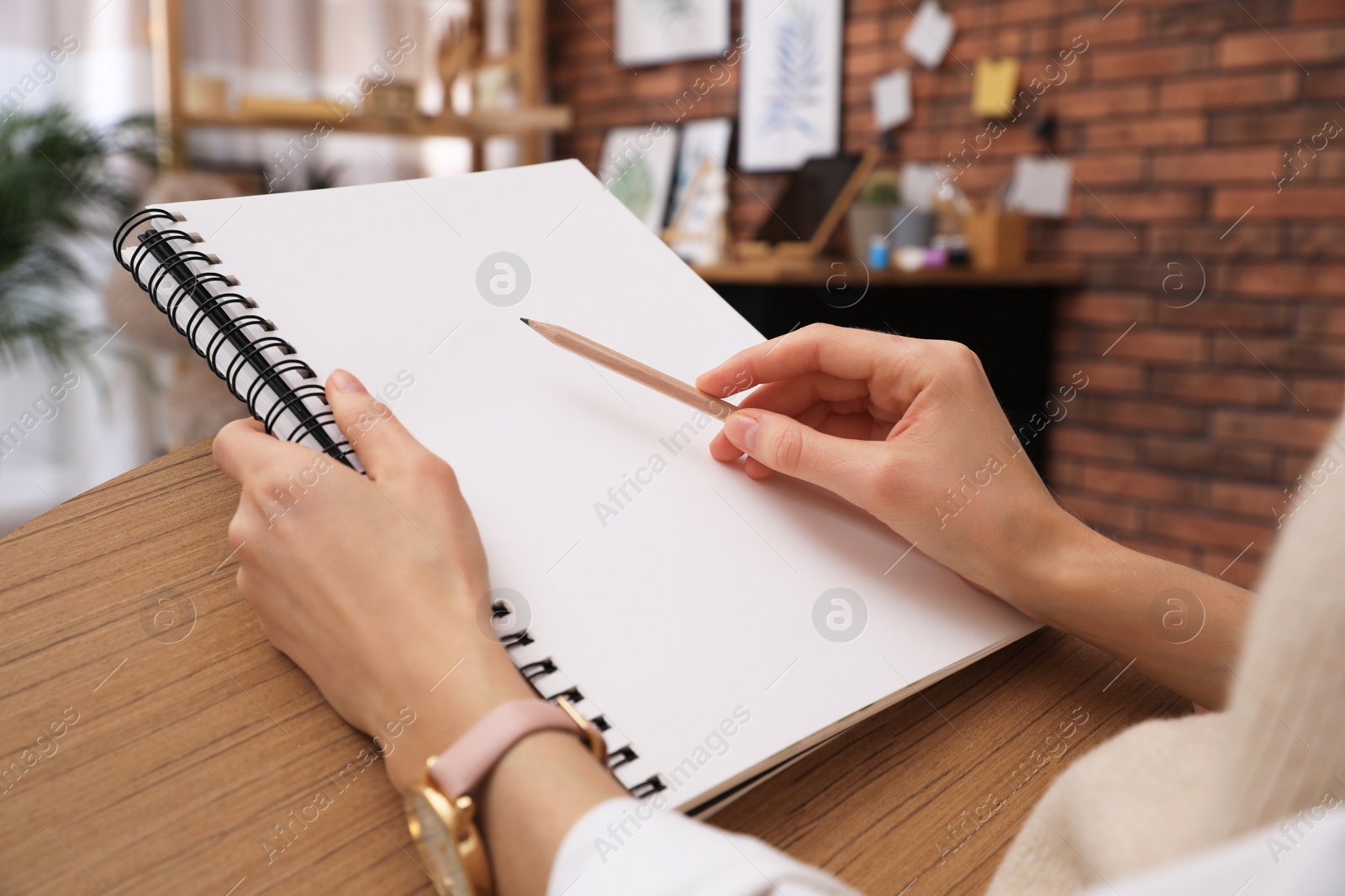 Photo of Woman drawing in sketchbook with pencil at home, closeup