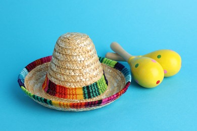 Photo of Mexican sombrero hat and maracas on light blue background