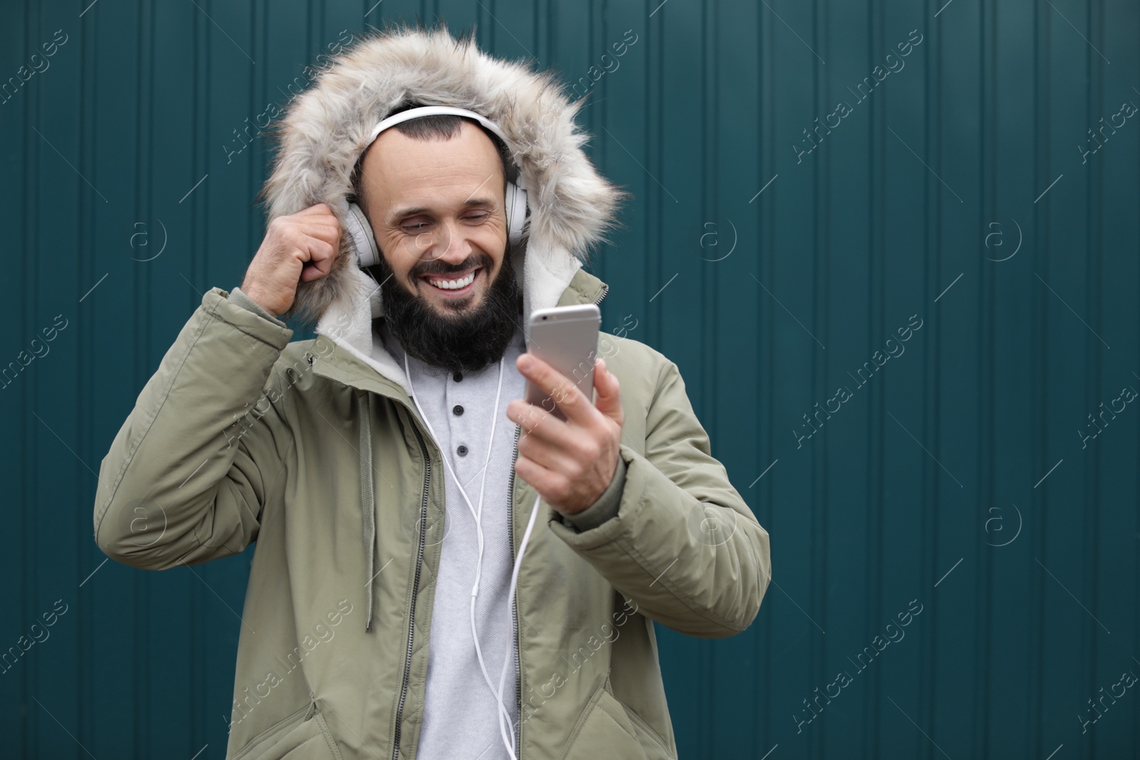 Photo of Mature man with headphones listening to music near color wall. Space for text