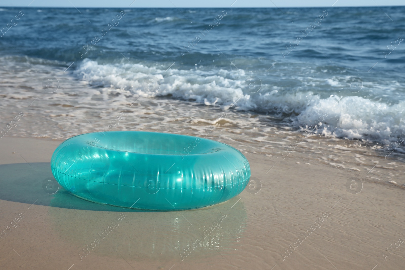 Photo of Bright inflatable ring on sandy beach near sea, space for text