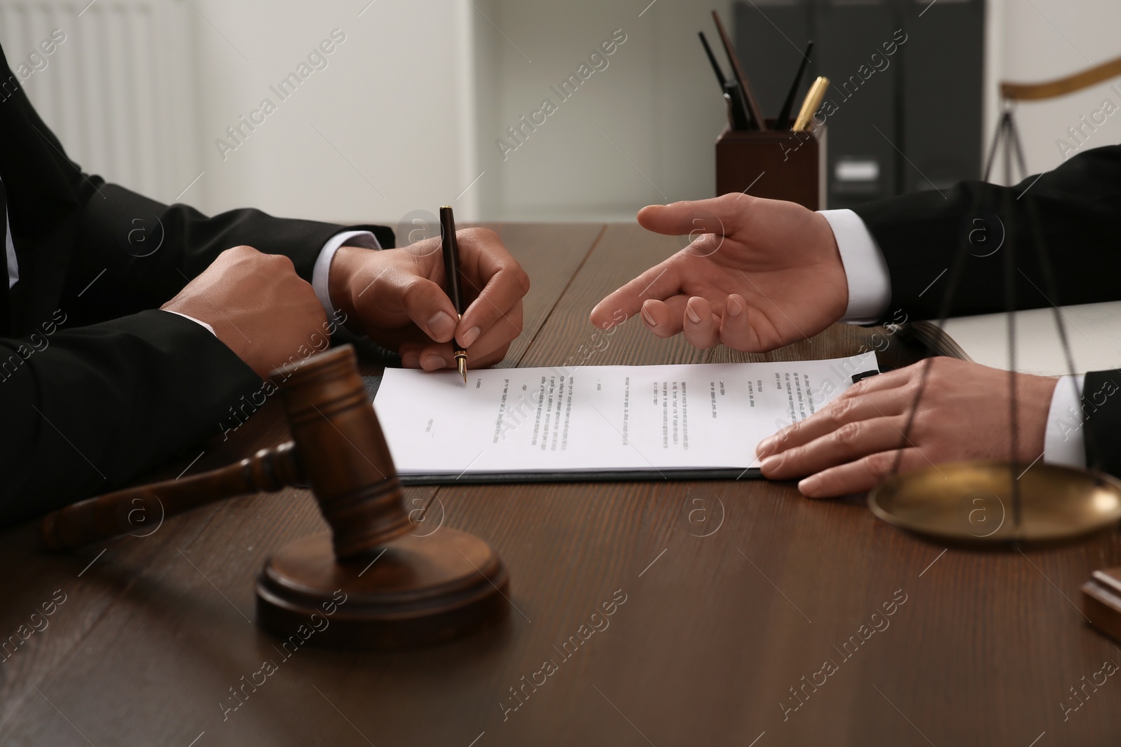 Photo of Law and justice. Lawyers working with documents at wooden table in office, closeup