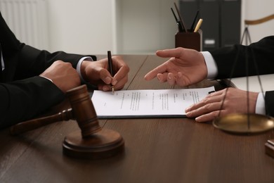 Photo of Law and justice. Lawyers working with documents at wooden table in office, closeup
