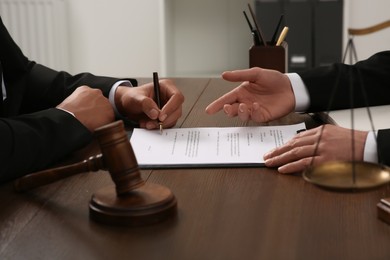 Law and justice. Lawyers working with documents at wooden table in office, closeup