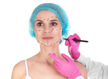 Doctor drawing marks on woman's face against white background. Cosmetic surgery