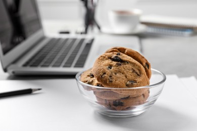 Photo of Bowl with chocolate chip cookies on white table in office, closeup. Space for text