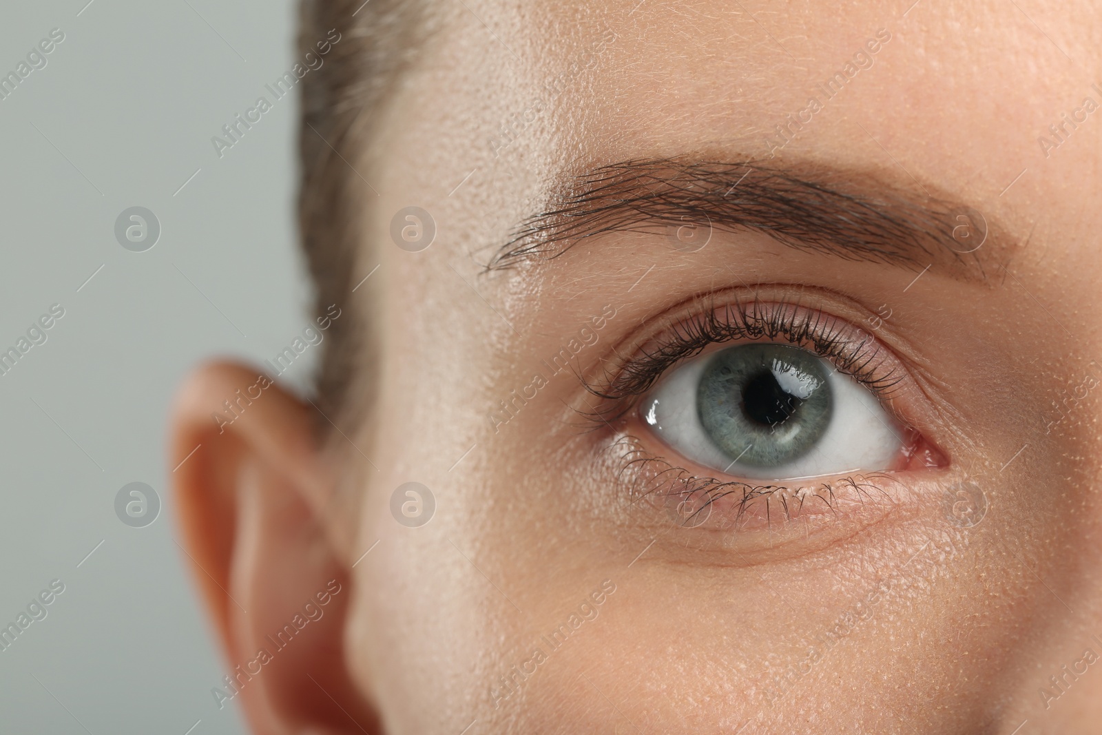 Photo of Woman with beautiful natural eyelashes on grey background, closeup