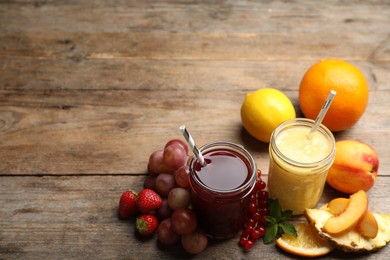 Photo of Delicious colorful juices in glasses and fresh ingredients on wooden table. Space for text