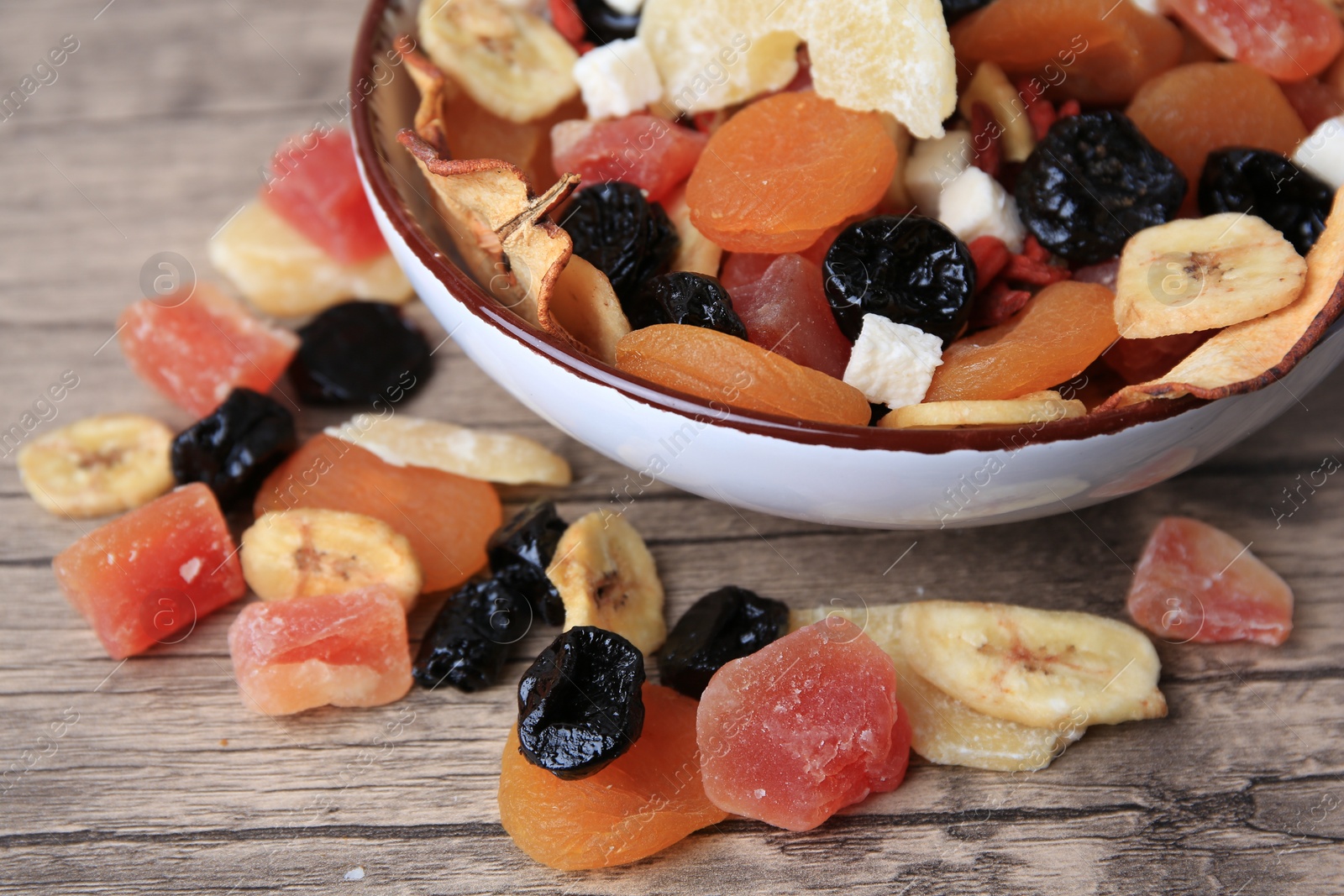 Photo of Bowl with different tasty dried fruits on wooden table, closeup