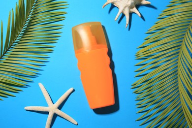 Flat lay composition with sunscreen and tropical leaves on light blue background. Sun protection care