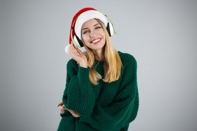 Photo of Happy woman with headphones on grey background. Christmas music