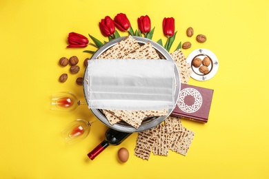 Image of Coronavirus pandemic. Flat lay composition with Passover matzos and protective face mask on yellow background