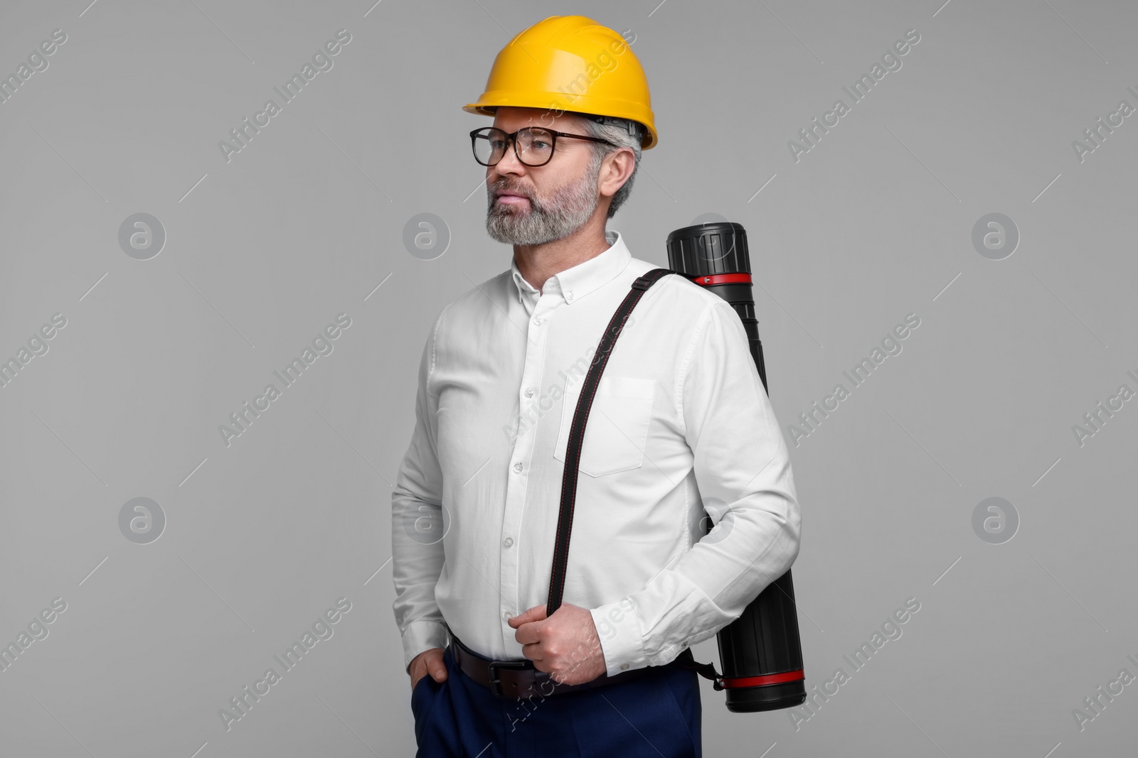 Photo of Architect in hard hat with drawing tube on grey background