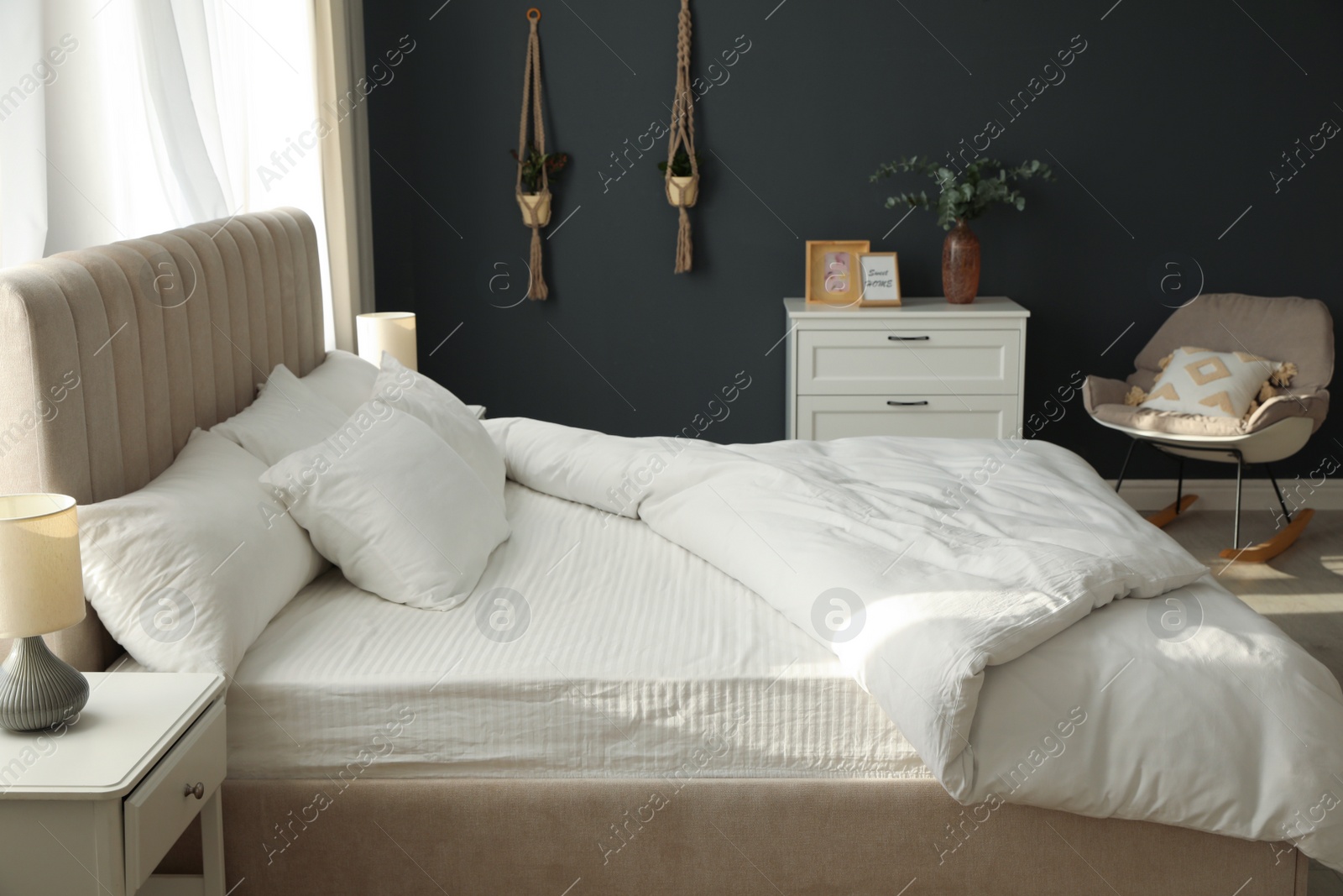 Photo of Comfortable bed with soft blanket in stylish room interior