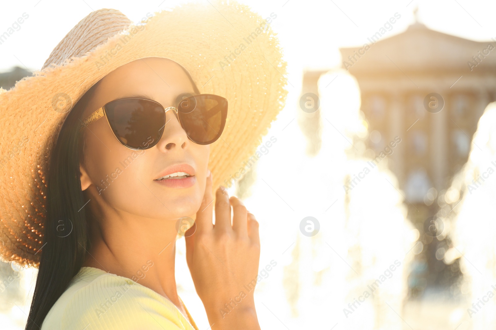 Photo of Beautiful young woman wearing stylish sunglasses outdoors, closeup. Space for text