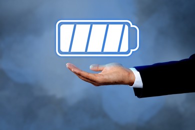 Businessman demonstrating at icon of full battery on color background, closeup