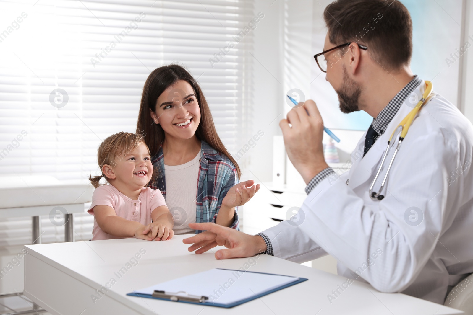 Photo of Mother and her cute baby having appointment with pediatrician in clinic. Doctor examining little girl