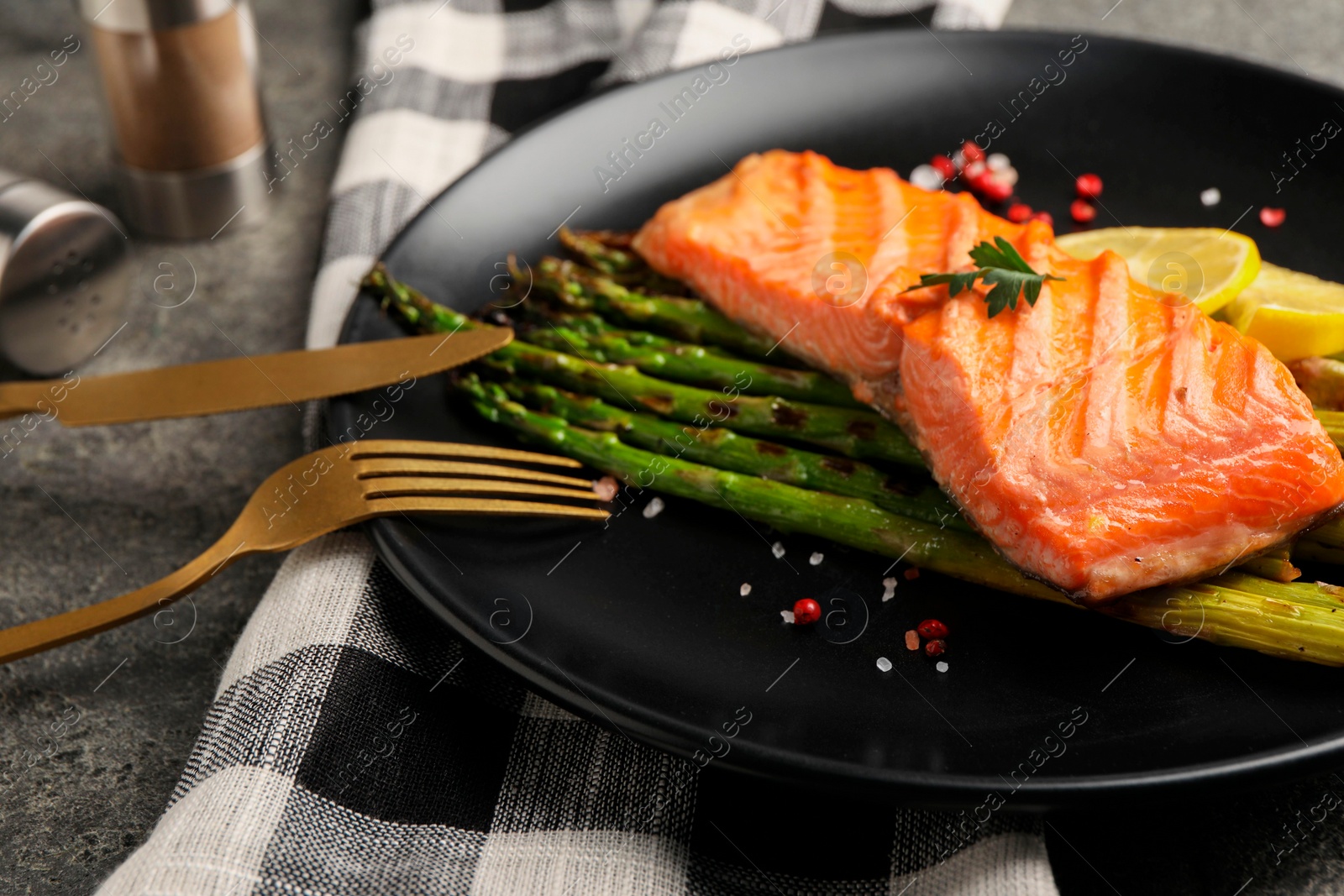 Photo of Tasty grilled salmon with asparagus and spices served on table, closeup