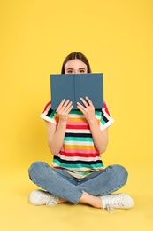 Photo of Young woman reading book on color background, space for text