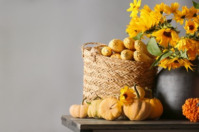 Beautiful autumn bouquet, small pumpkins and corn cobs on wooden table against grey background. Space for text