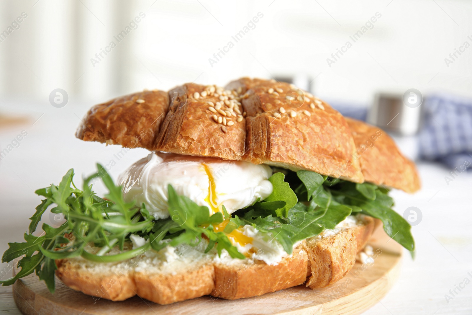 Photo of Delicious croissant with arugula and egg on white wooden table, closeup