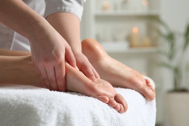 Photo of Woman receiving foot massage in spa salon, closeup