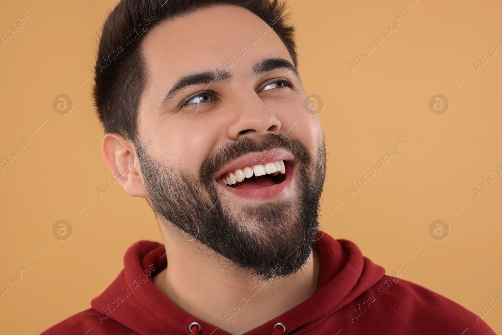 Photo of Handsome young man laughing on beige background, closeup