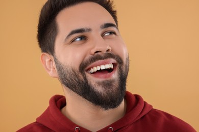 Handsome young man laughing on beige background, closeup