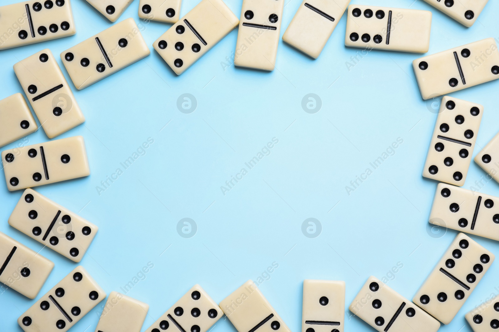 Photo of Frame of classic domino tiles on light blue background, flat lay. Space for text