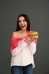 Photo of Young woman with tasty burger on grey background