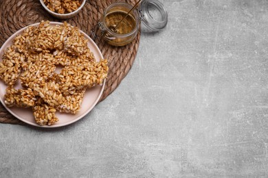 Photo of Plate with puffed rice bars (kozinaki) on grey table, above view. Space for text