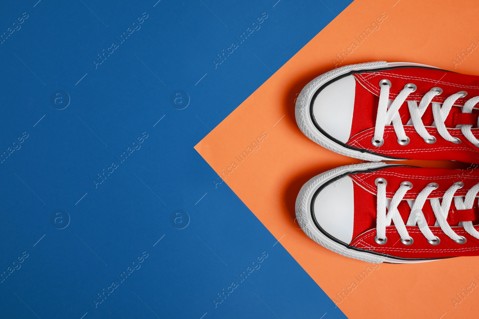 Photo of Pair of new stylish red sneakers on colorful background, flat lay. Space for text