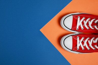 Photo of Pair of new stylish red sneakers on colorful background, flat lay. Space for text