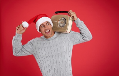Emotional man with vintage radio on red background. Christmas music