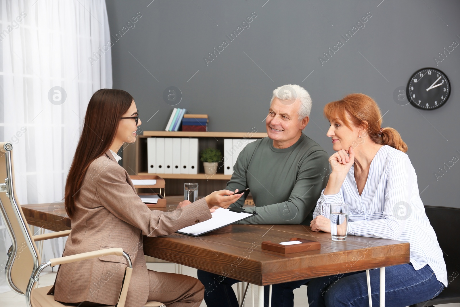 Photo of Young lawyer consulting senior couple in office