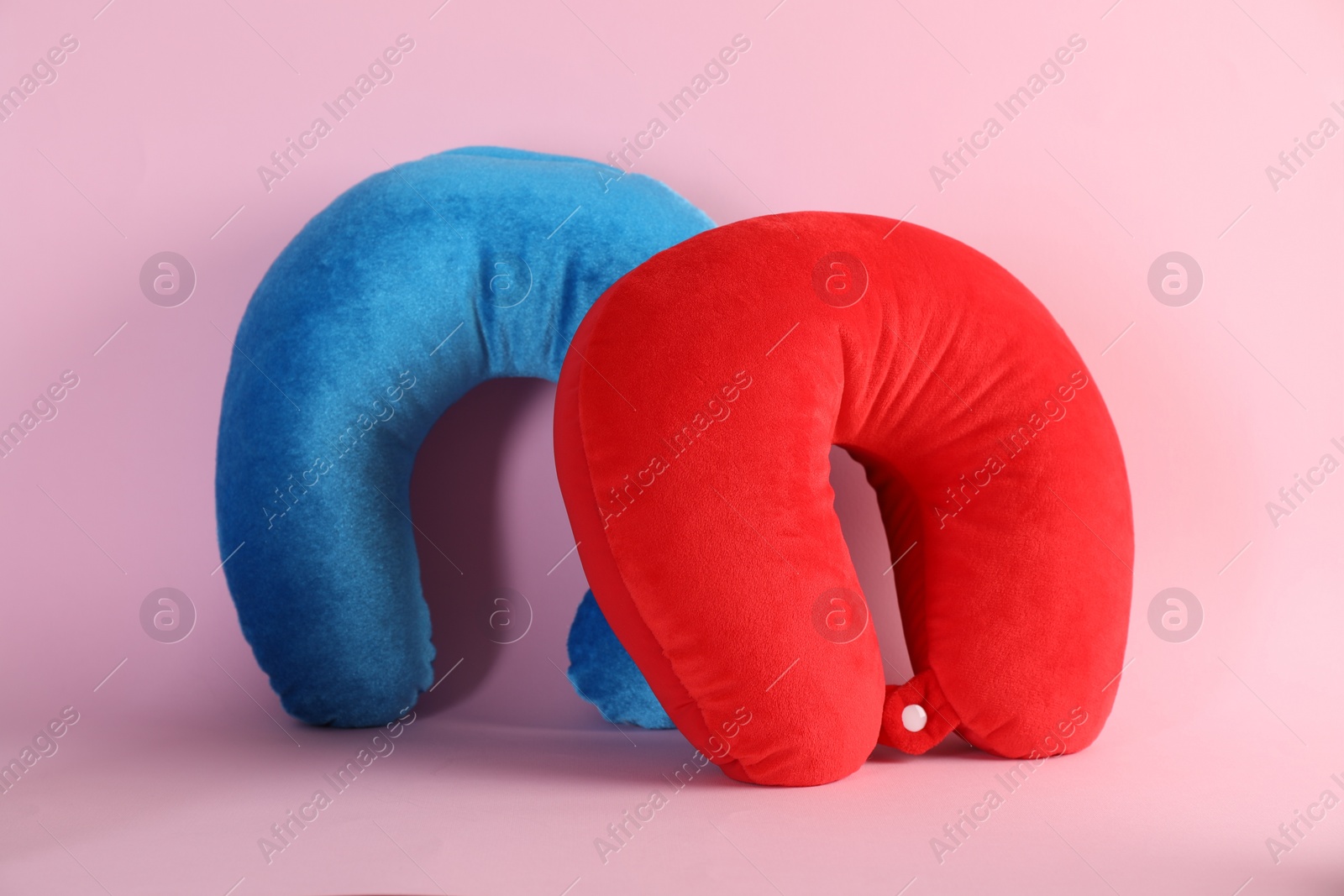 Photo of Light blue and red travel pillows on pink background