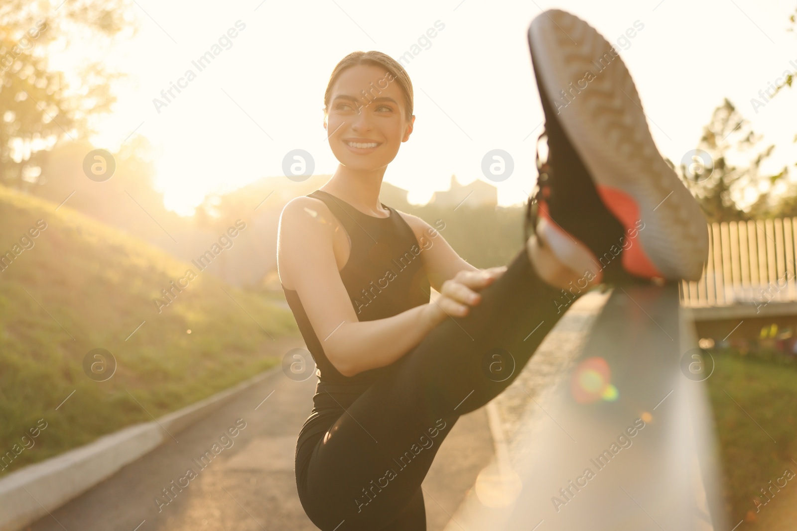 Photo of Attractive happy woman stretching outdoors on sunny day