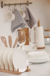 Photo of Drying rack with clean dishes on light table in kitchen