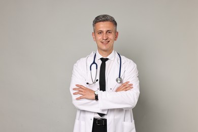 Photo of Happy doctor with stethoscope on grey background