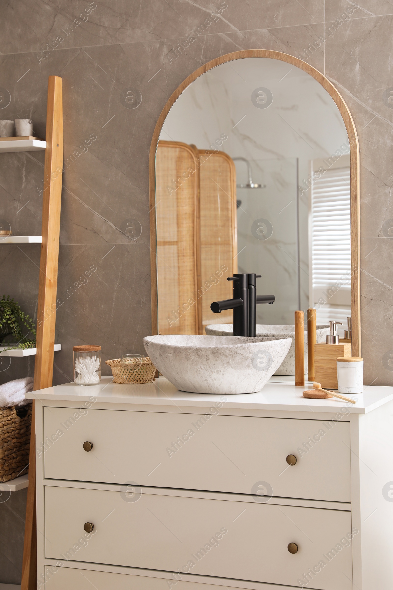 Photo of Chest of drawers with sink, mirror and toiletries in bathroom. Interior design