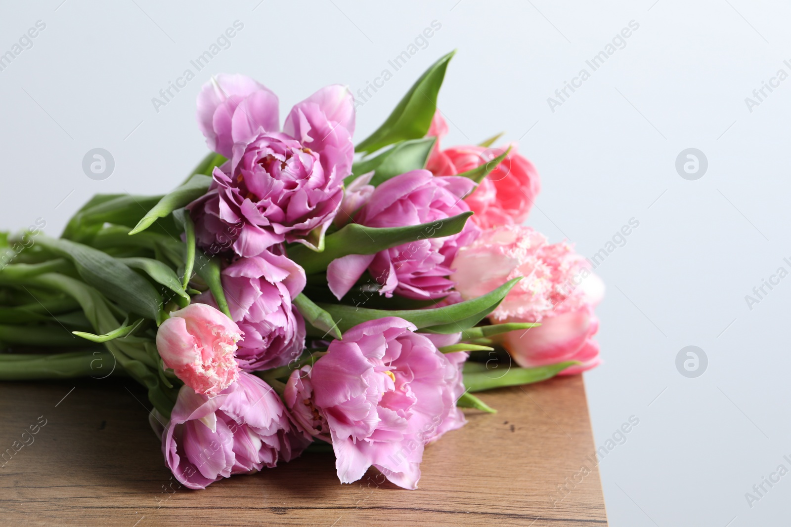 Photo of Beautiful bouquet of colorful tulip flowers on wooden table