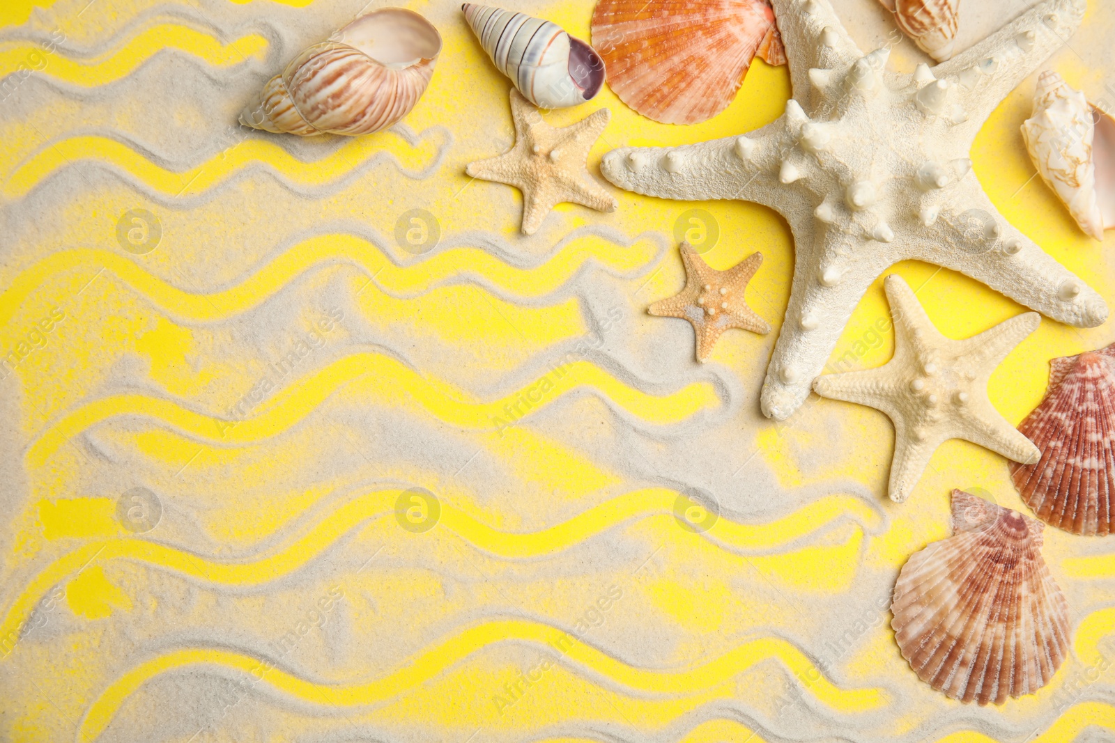 Photo of Beautiful sea stars, shells and sand on yellow background, flat lay