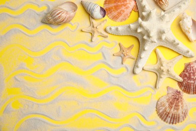 Beautiful sea stars, shells and sand on yellow background, flat lay