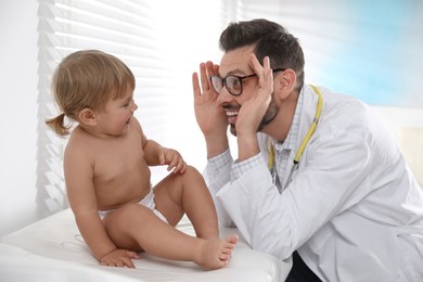 Photo of Pediatrician playing with cute baby during examination in clinic