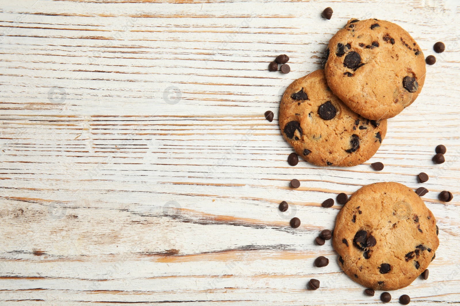 Photo of Delicious chocolate chip cookies on wooden table, flat lay. Space for text