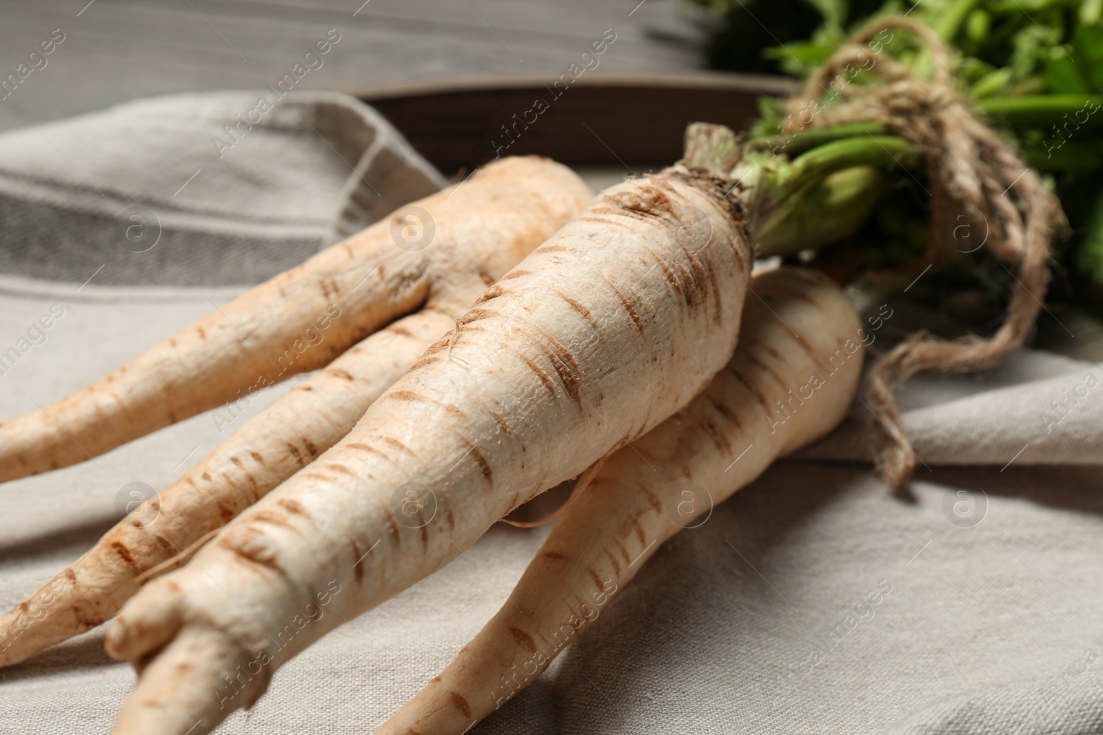 Photo of Delicious fresh ripe parsnips on kitchen towel, closeup