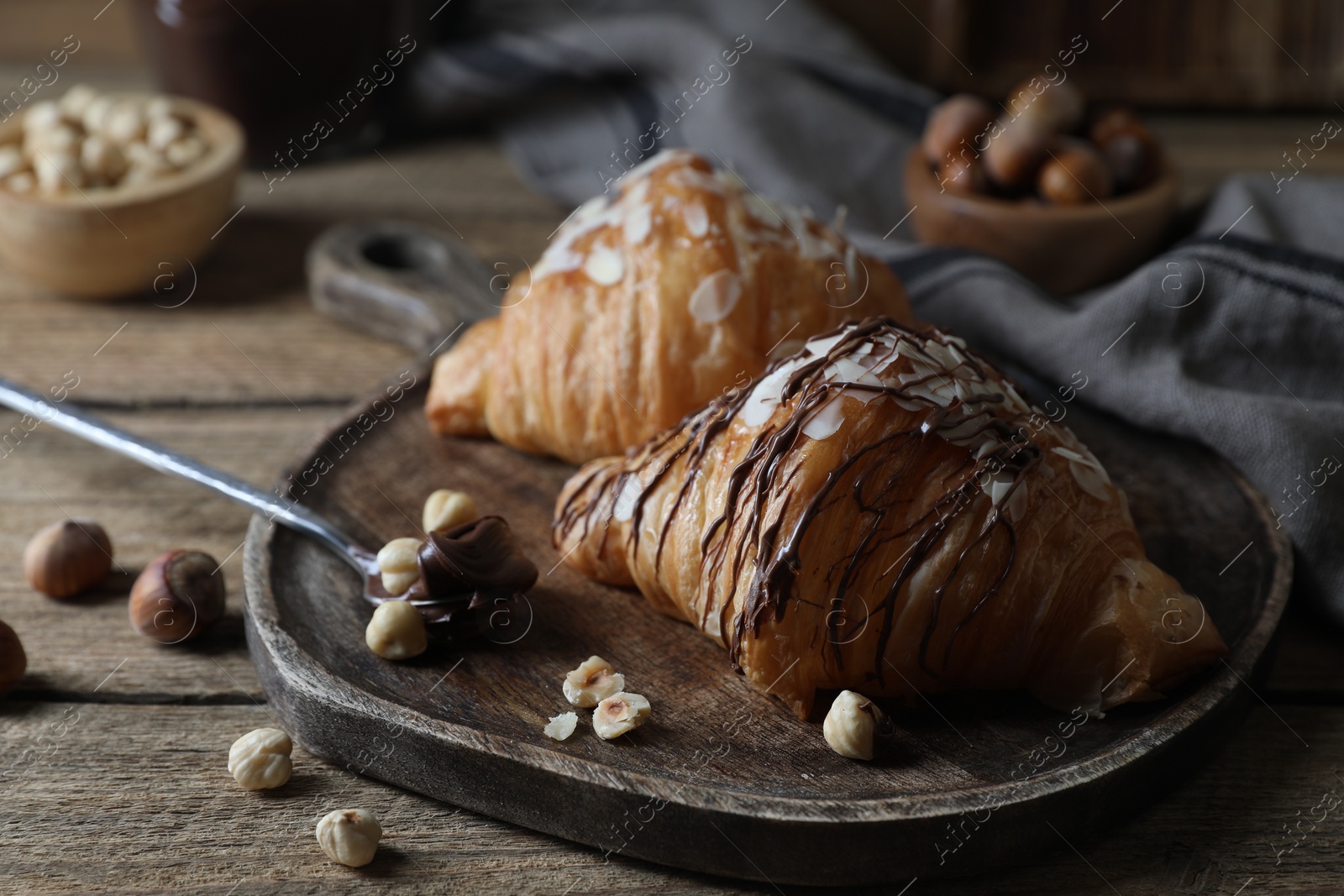 Photo of Delicious croissants with chocolate and nuts on wooden table