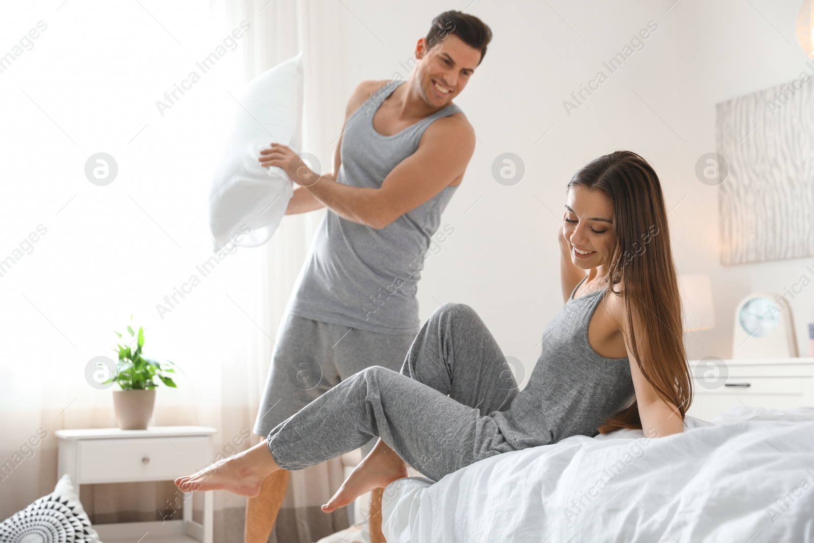 Photo of Happy young couple having pillow fight in bedroom