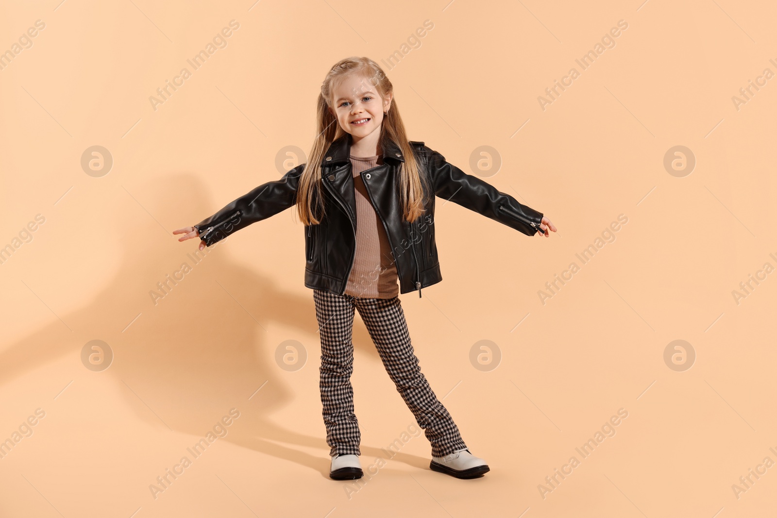 Photo of Fashion concept. Stylish girl posing on pale orange background