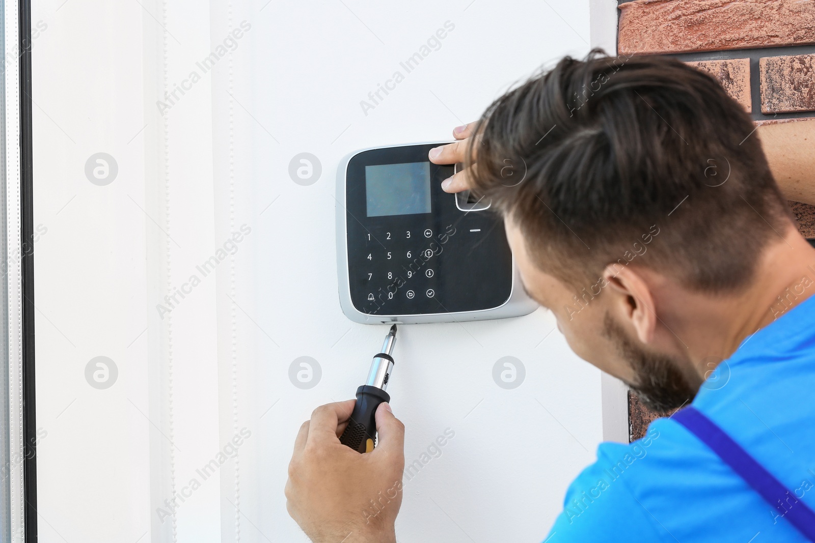 Photo of Male technician installing alarm system indoors