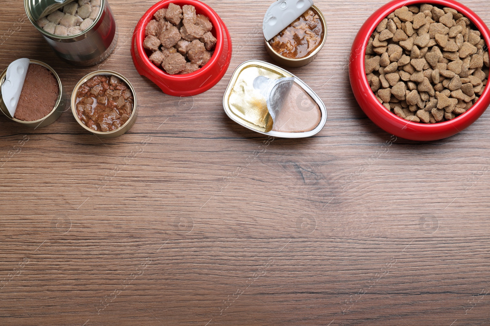 Photo of Wet and dry pet food on wooden table, flat lay. Space for text